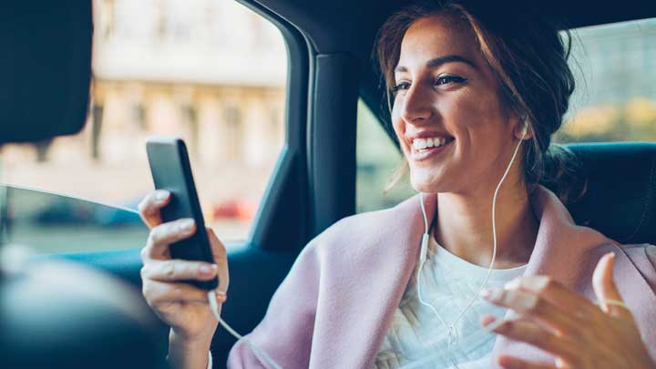 امرأة مبتسمة في سيارة تستخدم هاتفها