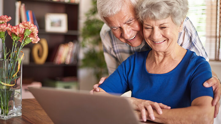 Elderly couple using a laptop in the confort of their house